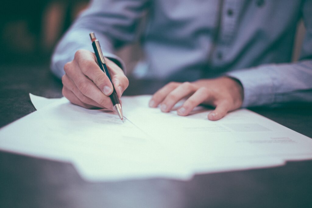 Business person holding a pen and writing on paper.