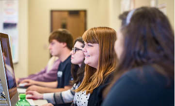 a row of students sitting at desktop computers in a classroom