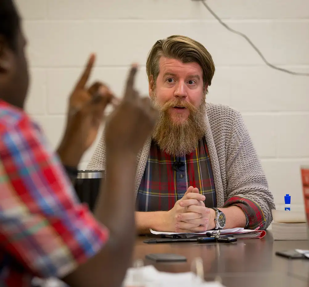 two graduate students discuss while sitting at a table
