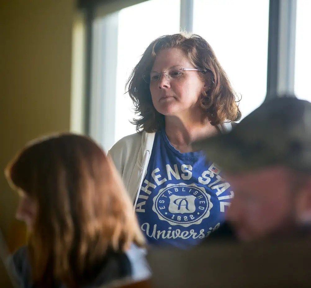 a female faculty member observes from the back of a classroom