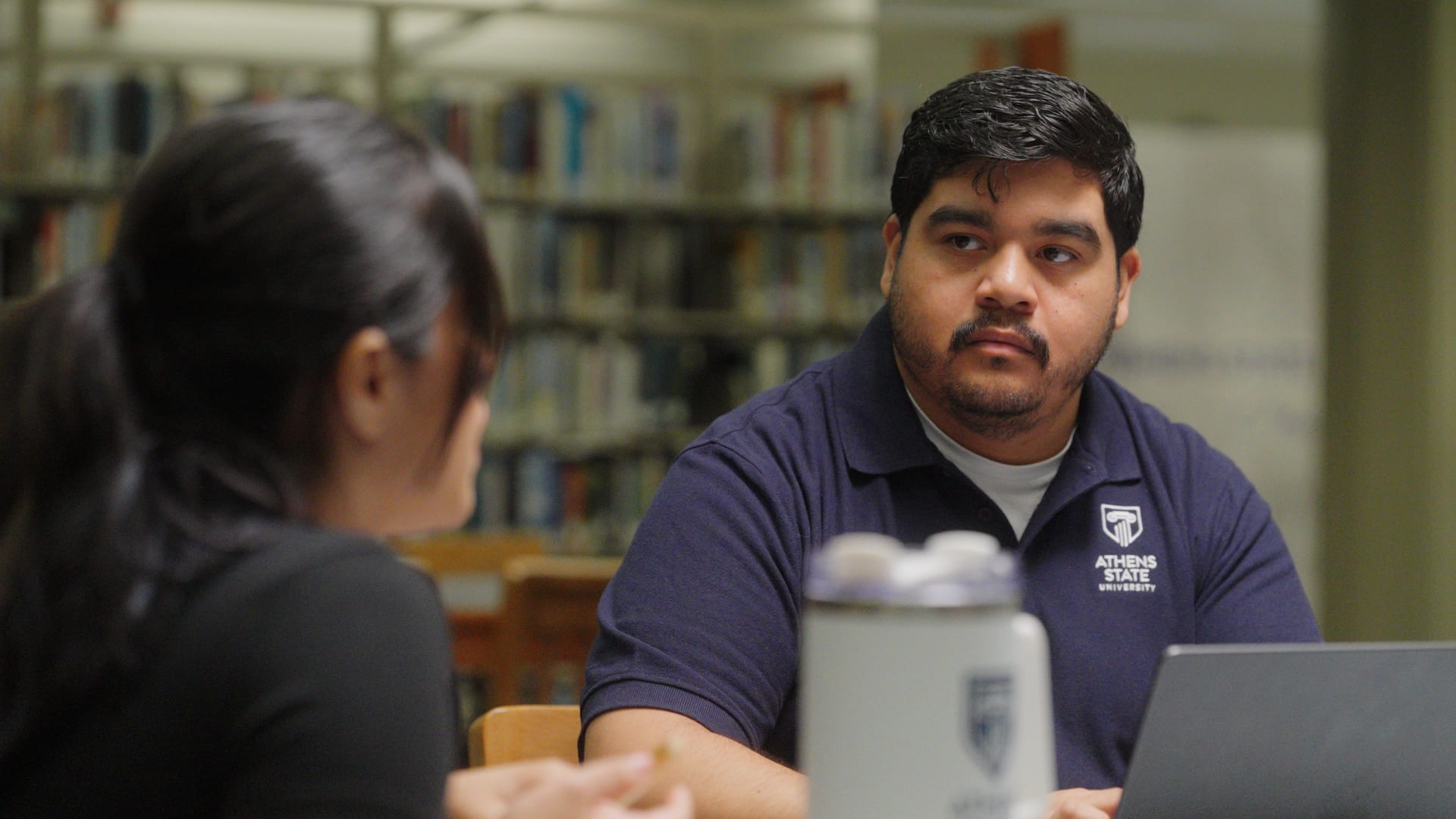 Advisor talking with student in library