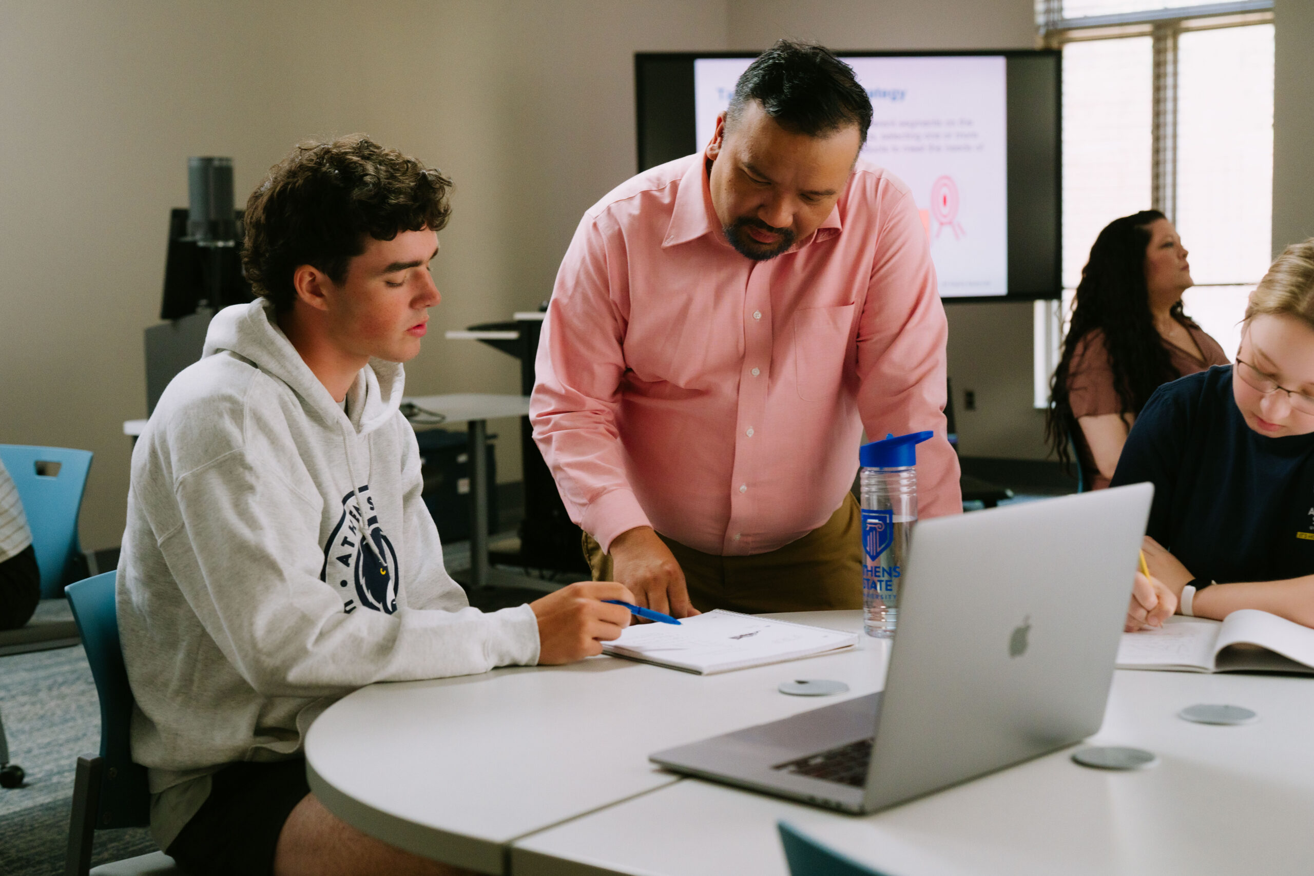 Professor provides guidance to student in a classroom