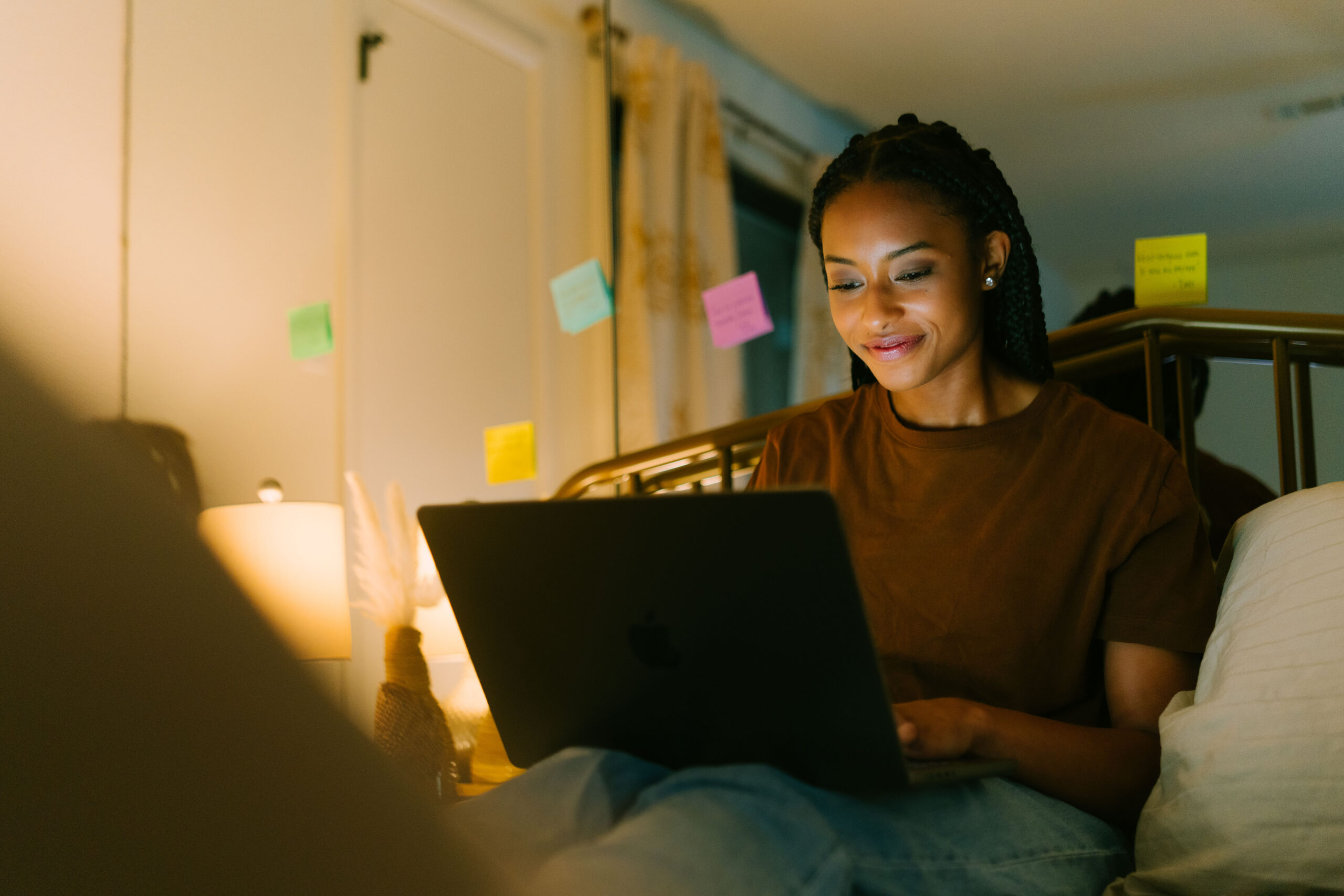 Student completes work on laptop while in bed