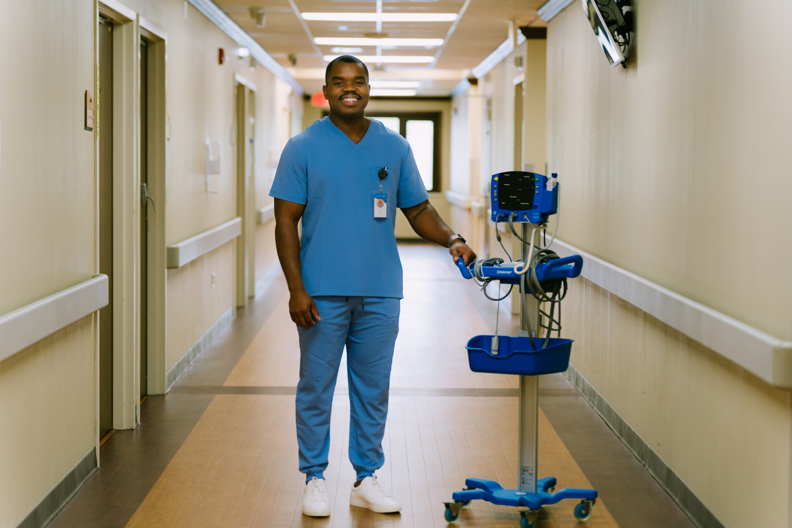 Nurse stands in hospital hallway with medical equipment