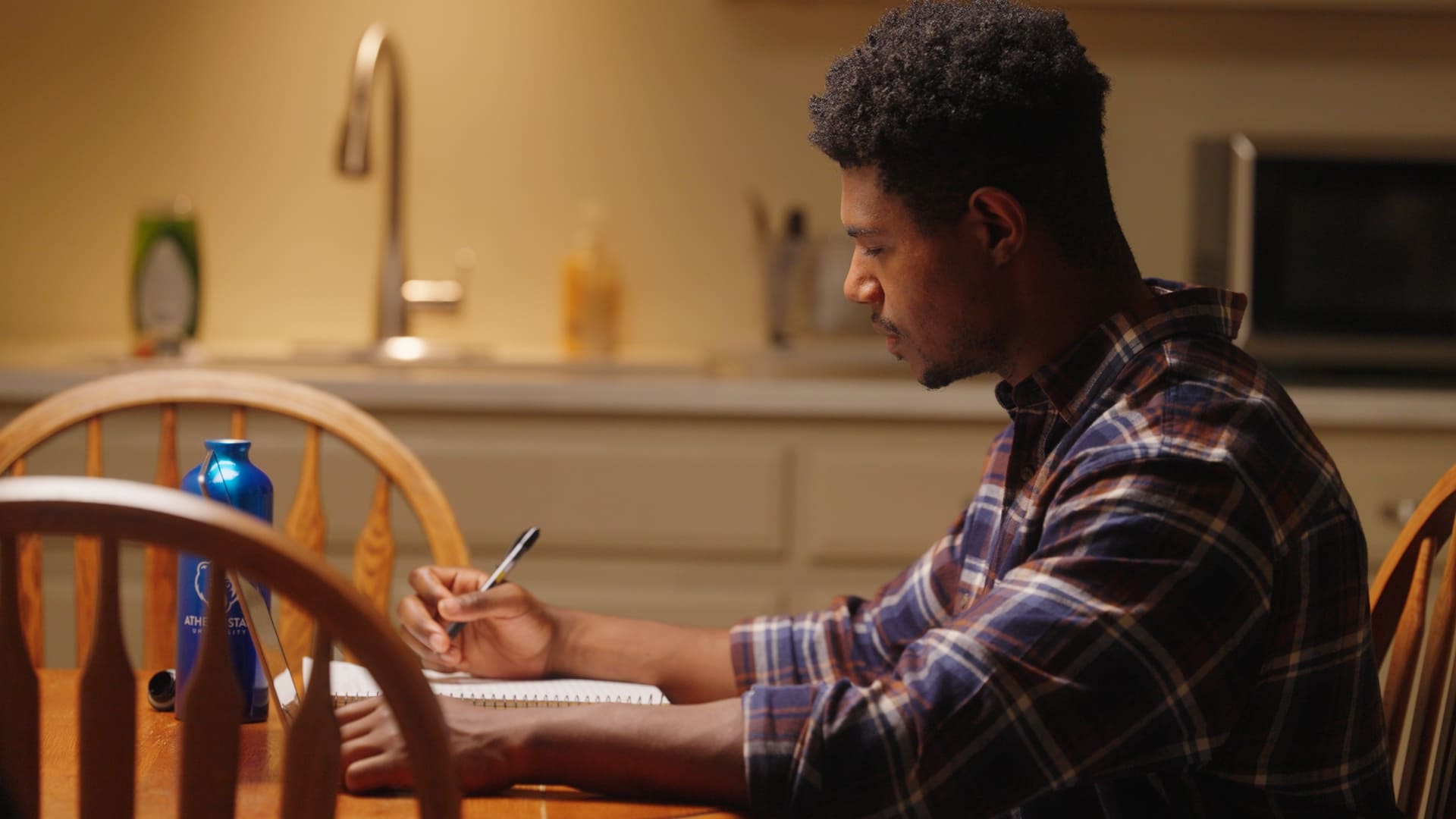 Student studying at kitchen table at night